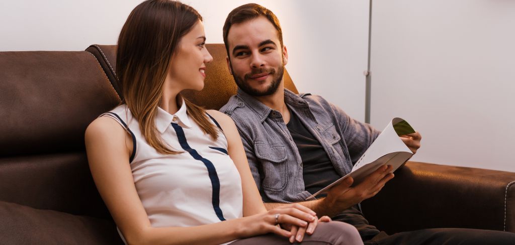 casal com papel em mãos olhando um para o outro e sorrindo